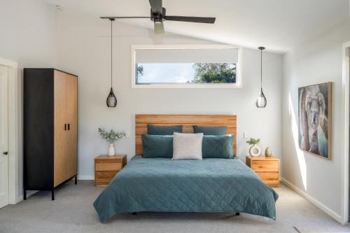 a bedroom with a blue bed and a window at Barrington Riverside Cottages in Barrington