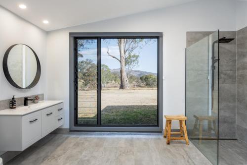a bathroom with a shower and a glass door at Barrington Riverside Cottages in Barrington