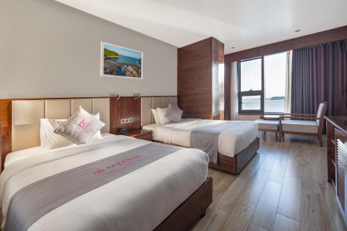 a hotel room with two beds and a balcony at Cat Ba Paradise Hotel - Sky Bar & Massage in Cat Ba