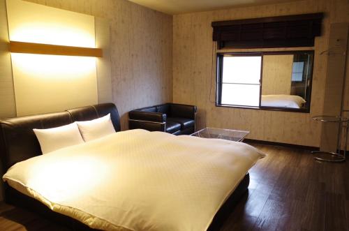 a bedroom with a bed and a chair and a window at Bar 39 in Higashihiroshima