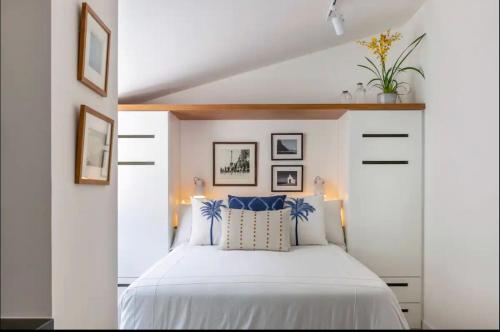 a bedroom with a white bed with blue pillows at STUDIO MONSIEUR 421 LEBLoN in Rio de Janeiro