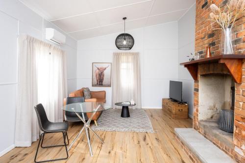 a living room with a glass table and a fireplace at Barrington Riverside Cottages in Barrington