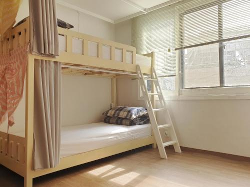 a bunk bed with a ladder in a room at Hongdae Cheese Guesthouse in Seoul