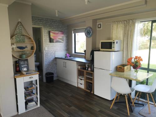 a kitchen with a white refrigerator and a table at Houhora Harbour Haven in Pukenui