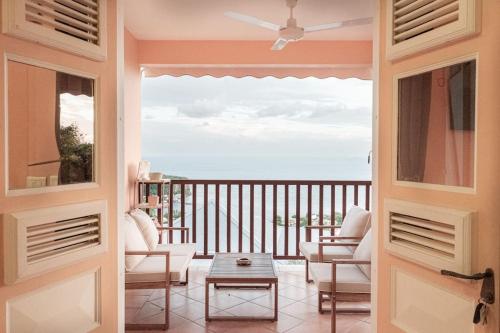 a door leading to a balcony with a view of the ocean at Villa T3 - Bleu Mer Caraïbes in Case-Pilote