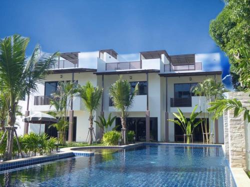 a villa with a swimming pool in front of a building at Oasis Garden & Pool Villa at VIP Resort in Ban Phe