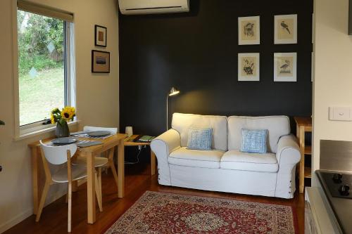 uma sala de estar com um sofá branco e uma mesa em Kaalba em Maleny