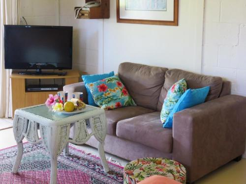 a living room with a couch and a table at Herons Reef Holiday Apartments in Rarotonga
