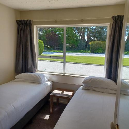 two beds in a room with a window at Flaxbourne Motels in Ward