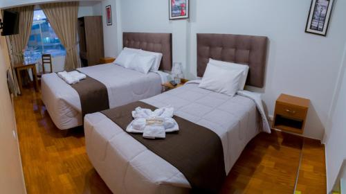 a hotel room with two beds with towels at Hostal Samakuy AQP in Arequipa