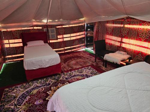 sypialnia z 2 łóżkami i krzesłem w namiocie w obiekcie Moon Light Camp w mieście Badīyah