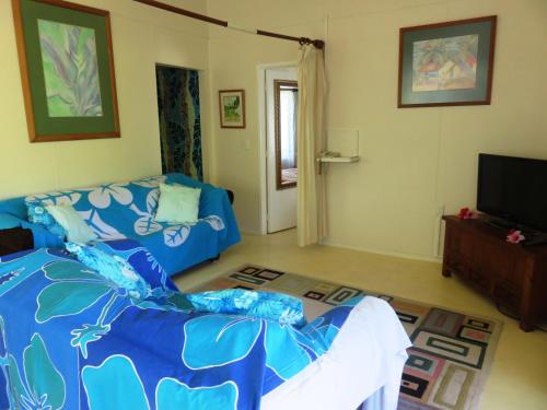 a living room with a blue bed and a tv at Herons Reef Holiday Apartments in Rarotonga