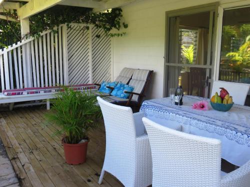 a table and chairs on a porch with a bottle of wine at Herons Reef Holiday Apartments in Rarotonga