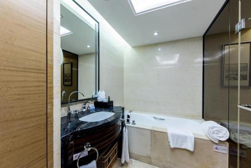 a bathroom with a tub and a sink and a mirror at Shenzhen LANGYUE International Hotel in Longgang