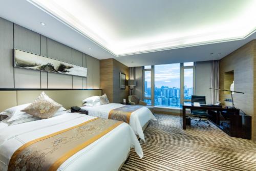 Shenzhen LANGYUE International Hotel في Longgang: غرفة فندقية بسريرين ومكتب