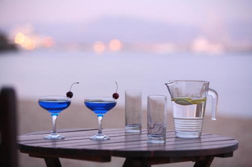 une table avec trois verres et un pichet de boisson bleue dans l'établissement Paros Inn, à Logaras