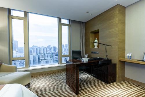 a room with a desk in a room with windows at Shenzhen LANGYUE International Hotel in Longgang