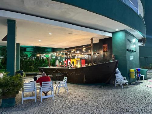 un hombre sentado en una mesa frente a un bar en Duplex Vista Mar Angra Inn, en Angra dos Reis