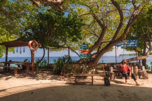 a woman sitting on a swing under a tree on the beach at Thundi Village & Spa in Maalhos