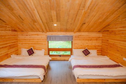 a bedroom with two beds in a log cabin at Meo Vac Valley in Mèo Vạc
