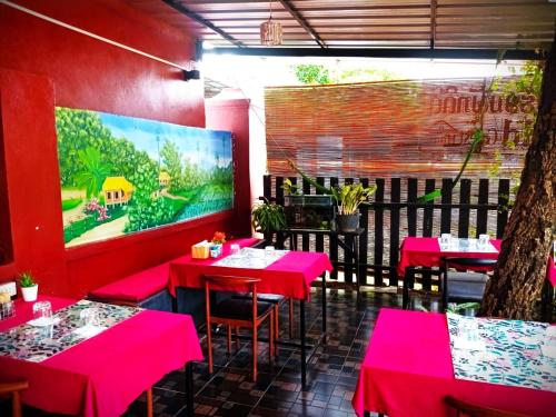 a dining room with pink tables and a large screen at Dee-Dee's Guest House, Bed And Breakfast in Pakse