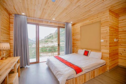 een slaapkamer met een bed en een groot raam bij Meo Vac Valley in Mèo Vạc