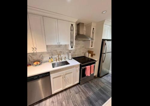 uma cozinha com armários brancos e electrodomésticos de aço inoxidável em Ocean Villa -1BDR- King bed- Kitsilano beach w/parking em Vancouver