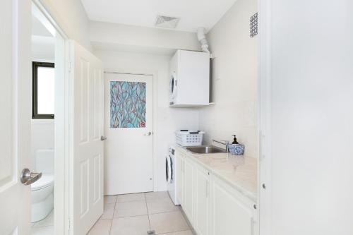 a white kitchen with white cabinets and a sink at Agathas at Seacombe Gardens in Sturt