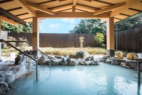 a pool of water in a yard with a wooden gazebo at Toba International Hotel Shiojitei in Toba