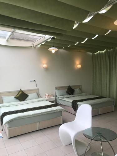 a bedroom with two beds and a table and a chair at Yun Ting Orchid Garden in Sanyi