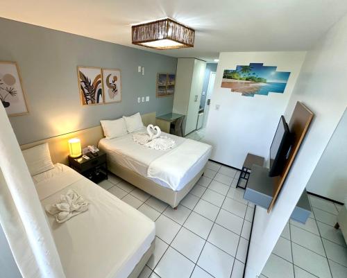 a hotel room with two beds and a television at Barreirinhas Gran Lençóis Flat in Barreirinhas