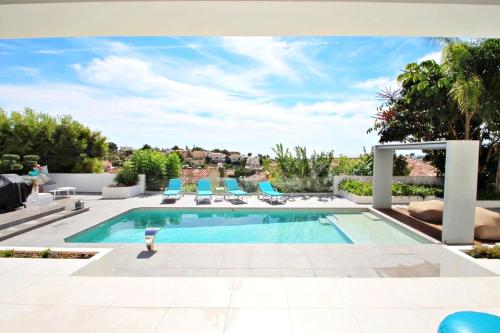 - une piscine dans une cour avec des chaises bleues dans l'établissement El Olivo - villa with stunning views and private pool in Benissa, à Benissa