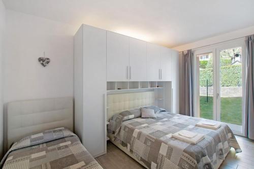 sypialnia z 2 łóżkami i dużym oknem w obiekcie Appartamenti Zerboni w mieście Lenno