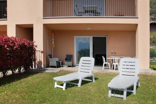 two white chairs sitting in the grass in front of a house at Appartamenti Zerboni in Lenno