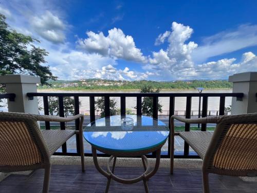 a glass table on a balcony with a view of the water at Chiangkhong Teak Garden Riverfront Onsen Hotel- SHA Extra Plus in Chiang Khong
