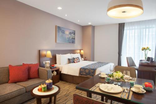 a hotel room with a bed and a couch and a table at Somerset Central TD Hai Phong City in Hai Phong