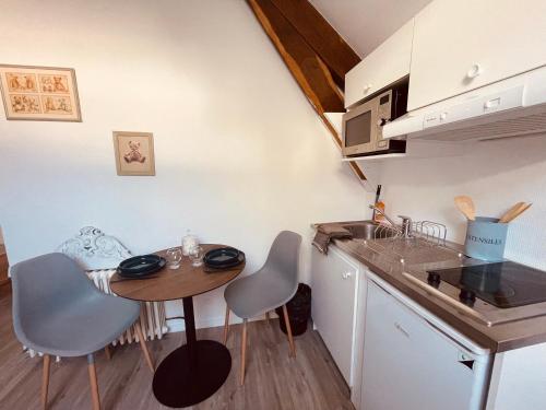 Les Suites du 119 في فان: مطبخ صغير مع طاولة وكراسي ومغسلة