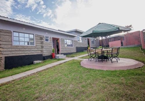 a patio with a table and chairs and an umbrella at Ebony Mara - Green House in Narok