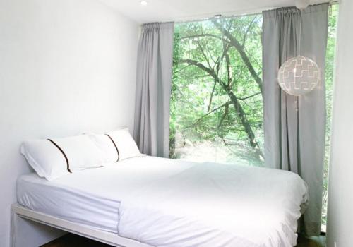 uma cama branca num quarto com uma janela em Time Capsule Retreat, Sungai Lembing em Sungai Lembing