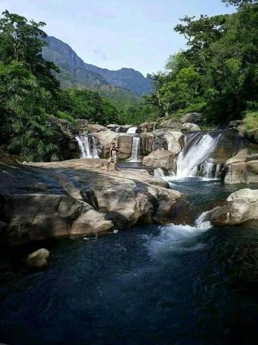 a group of waterfalls in a river with rocks at Abimansala Resort in Hunnasgiriya