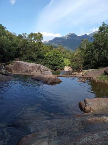 a river with rocks and trees and mountains in the background at Abimansala Resort in Hunnasgiriya
