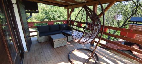 a porch with a hammock and a bench on a deck at Vikendica Popović in Doboj