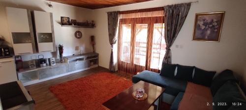 sala de estar con sofá, mesa y ventana en Vikendica Popović en Doboj