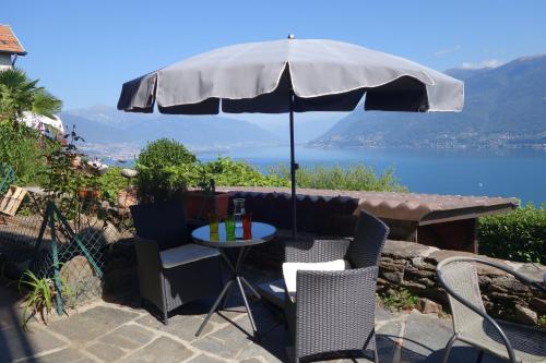 a table and chairs under an umbrella on a patio at Dream vacation on the lake in Brissago