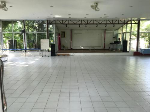 a large room with a stage and a white tiled floor at Sripiamsuk Resort Bangkok in Pathum Thani