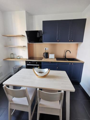 een keuken met een tafel, 2 stoelen en een wastafel bij Charmant appartement proche de la gare in Vichy