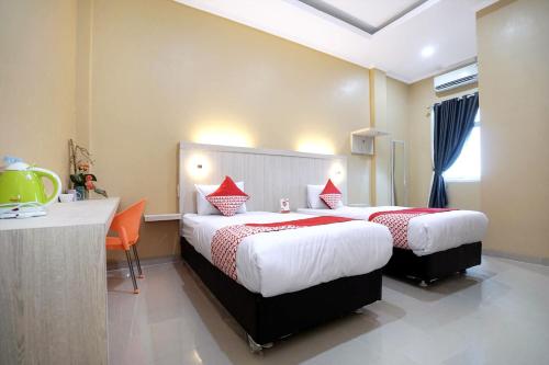 a hotel room with two beds and a desk at OYO Life 1299 Balcony Orange Homestay in Palembang