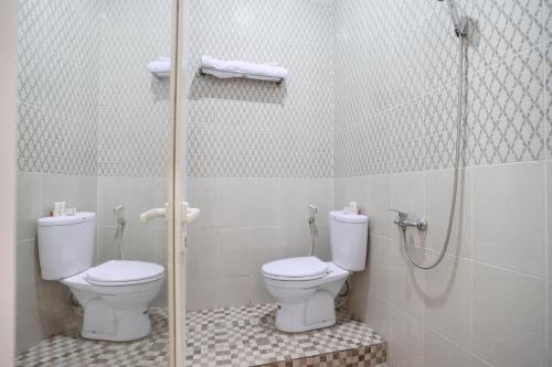 a bathroom with a shower and a toilet and a glass shower door at OYO Life 1299 Balcony Orange Homestay in Palembang