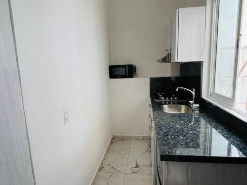 a small white kitchen with a sink and a window at Mini Departamento Real del Country Playa Alberca in Manzanillo