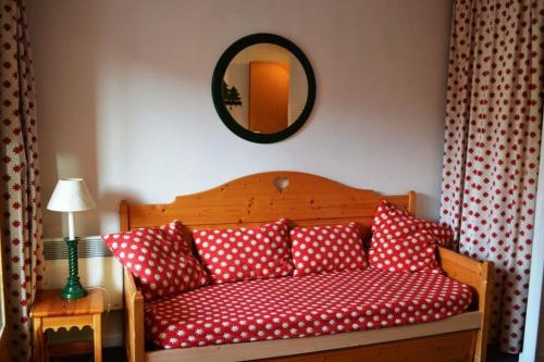 - un canapé rouge avec des oreillers à point de polka et un miroir dans l'établissement T2 six couchages, exposé sud, sur les pistes, à Risoul
